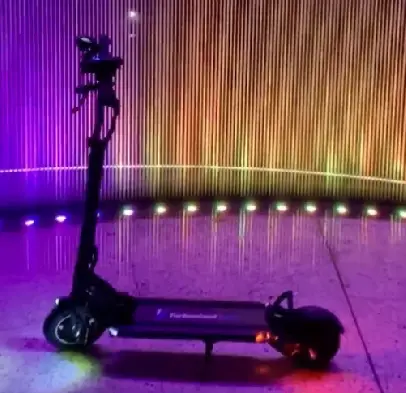 side view of a Turbowheel Swift electric scooter leaning on its stand in a room with purple lighting