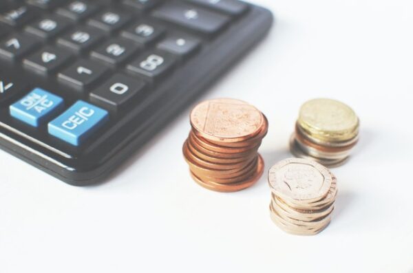 3 sets of coins of different sizes next to a calculator