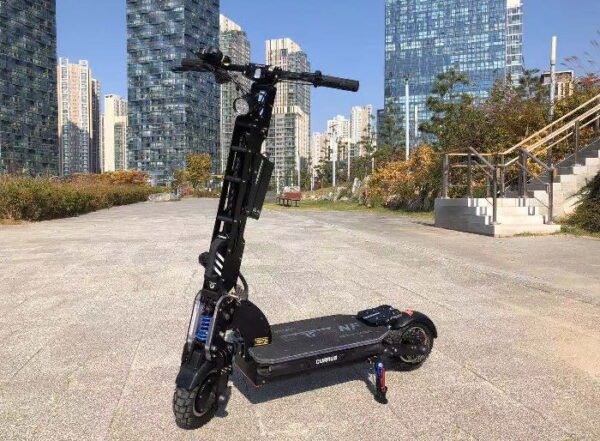 front diagonal view of a black Currus NF electric scooter leaning on its stand in an urban environment with tall buildings in background