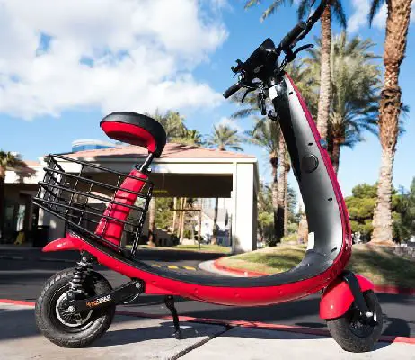 side view of a red Ford Ojo electric scooter with black details in an everyday environment