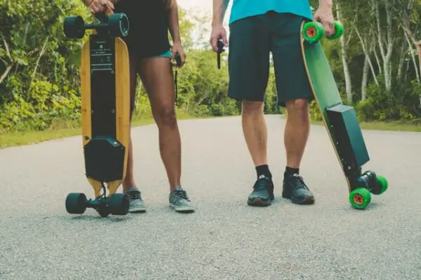 two people each holding an electric skateboard