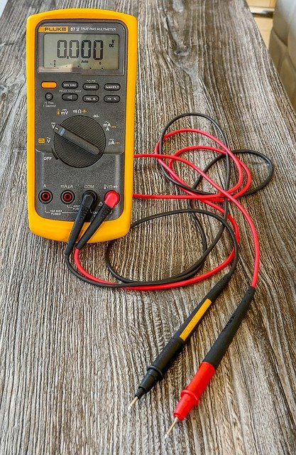 voltage meter on a desk with a red and a black cable plugged in it