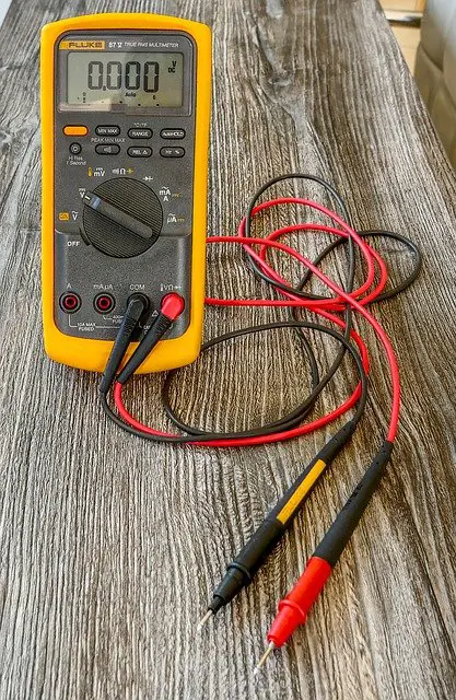 voltage meter on a desk with a red and a black cable plugged in it