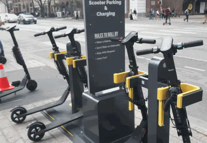 4 electric scooters getting charged at a charging station