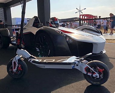 white Rion electric scooter standing next to a racing car