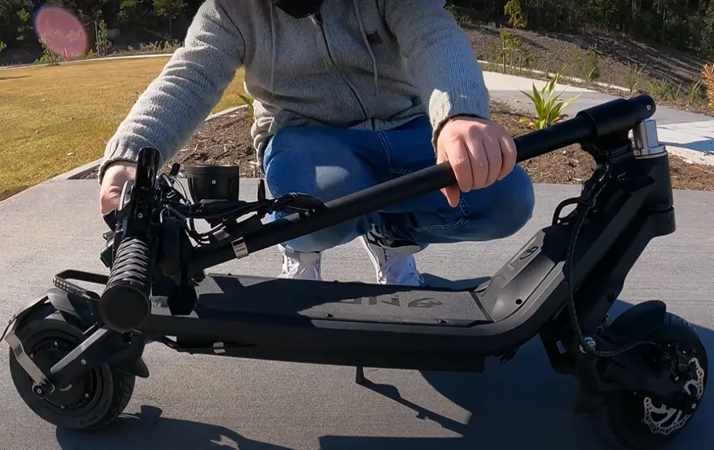 A closeup of a man folding the Nami Klima e-scooter