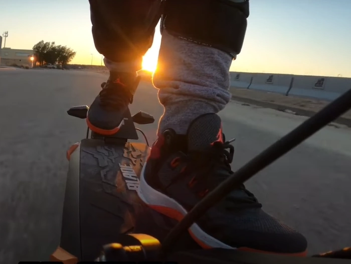 A closeup of a person's feet standing on the deck of the Blade 10 GT+ e-scooter