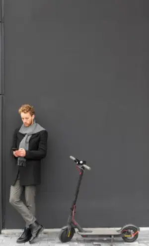 A man standing next to an electric scooter