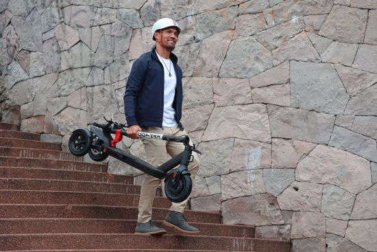 A guy carrying a folded electric scooter down steps