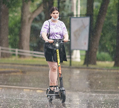 A woman riding an electric scooter in the rain