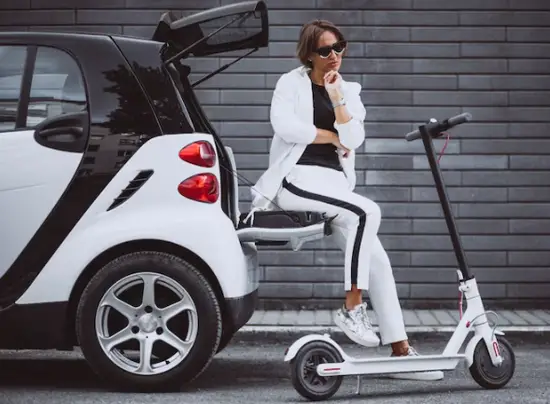 A woman standing next to an electric scooter