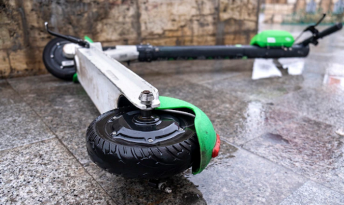 An electric scooter lying on a wet ground