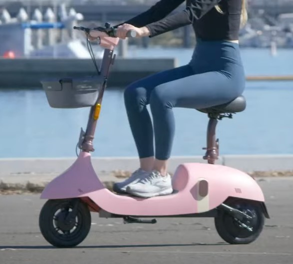 person riding a pink OKAI Beetle