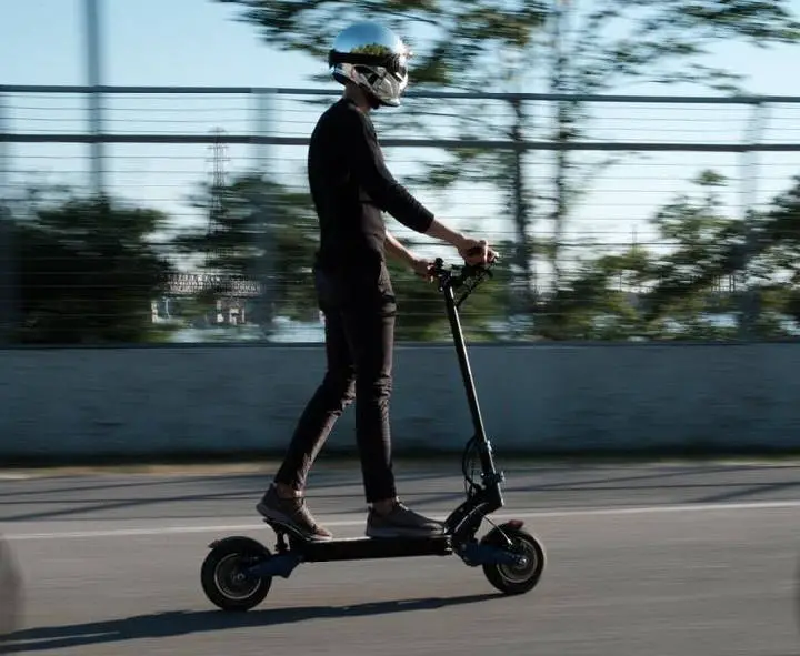 person with a helmet riding an Apollo Pro electric scooter on a street