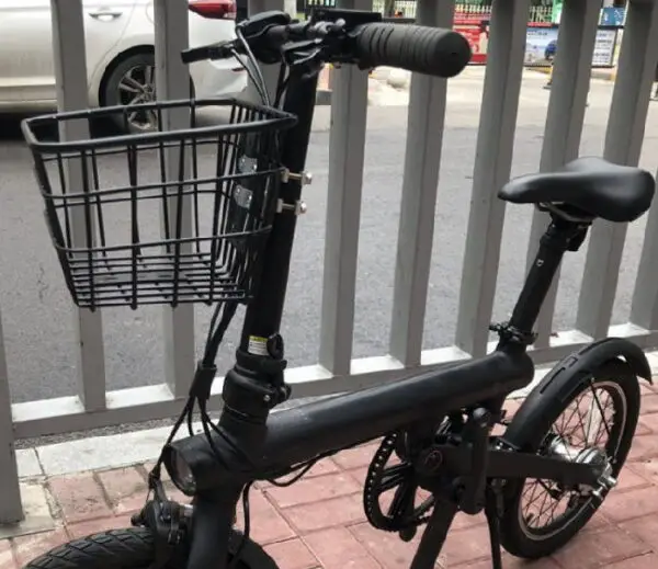 small black electric scooter with a seat and a basket in the front