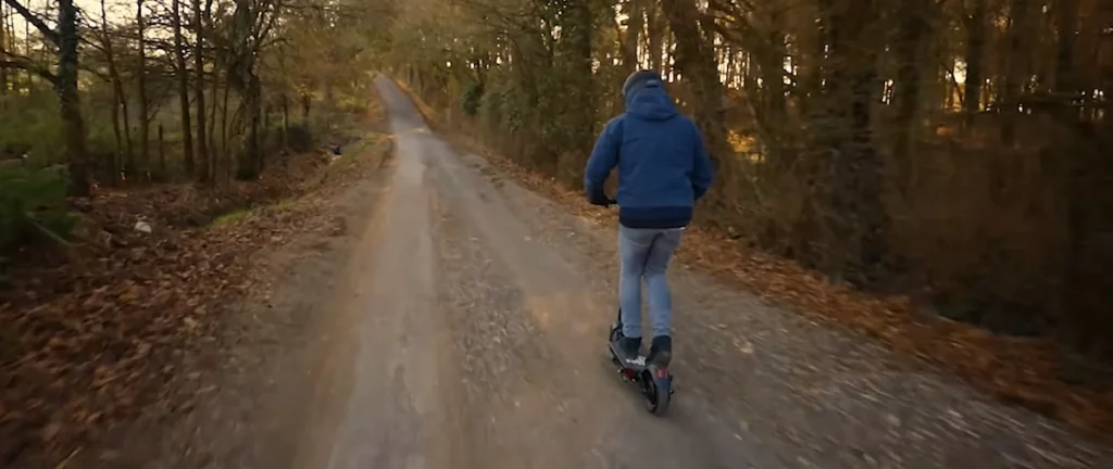 a guy climbing hill with his electric scooter.