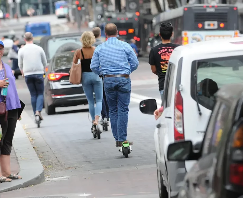 man and woman on electric scooters in a traffic jam