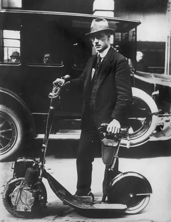 black and white photograph of a person holding a folding motorized scooter