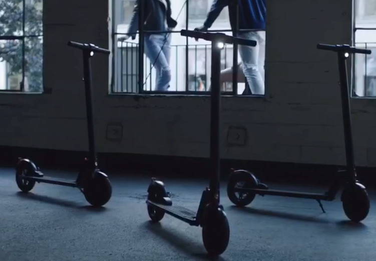 three GoTrax GXL V2 Commuter scooters in a dark room