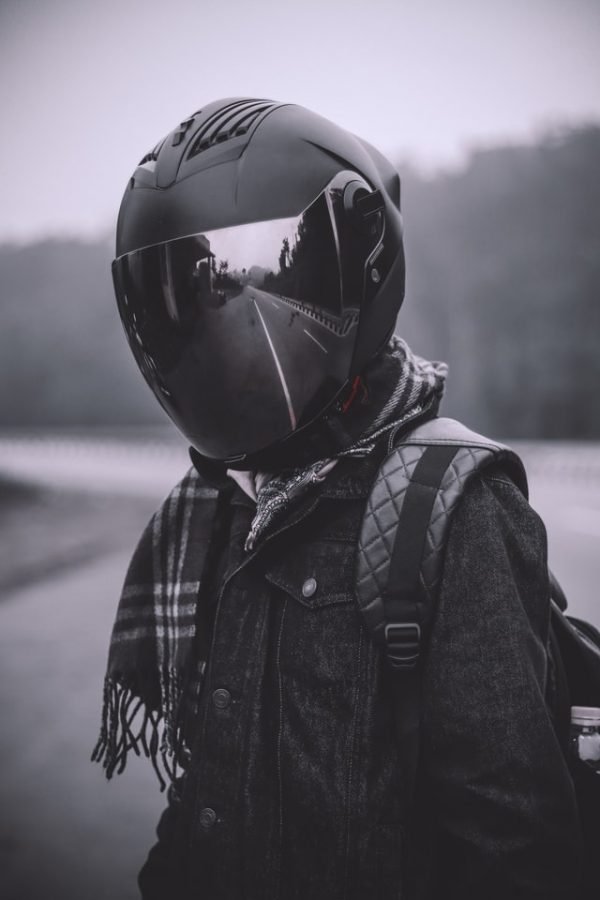 Person wearing a black reflective full motorcycle helmet and a backpack