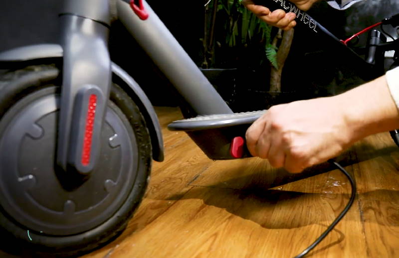 person plugging in a charger in a Macwheel MX Pro electric scooter