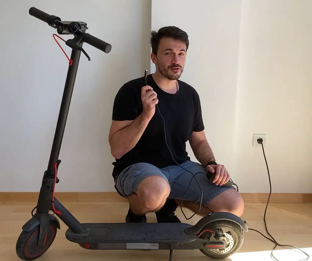 person showing how to charge an Xiaomi M365 Pro electric scooter