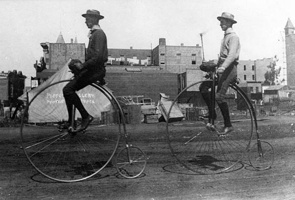 two people riding Pennyfarthing bicycles