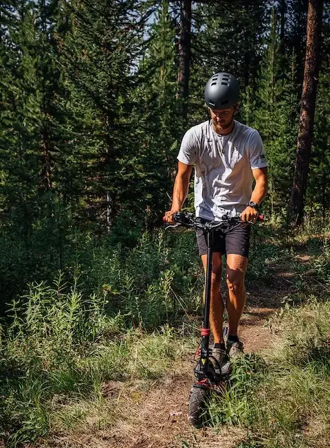 person riding an electric scooter on a forest path