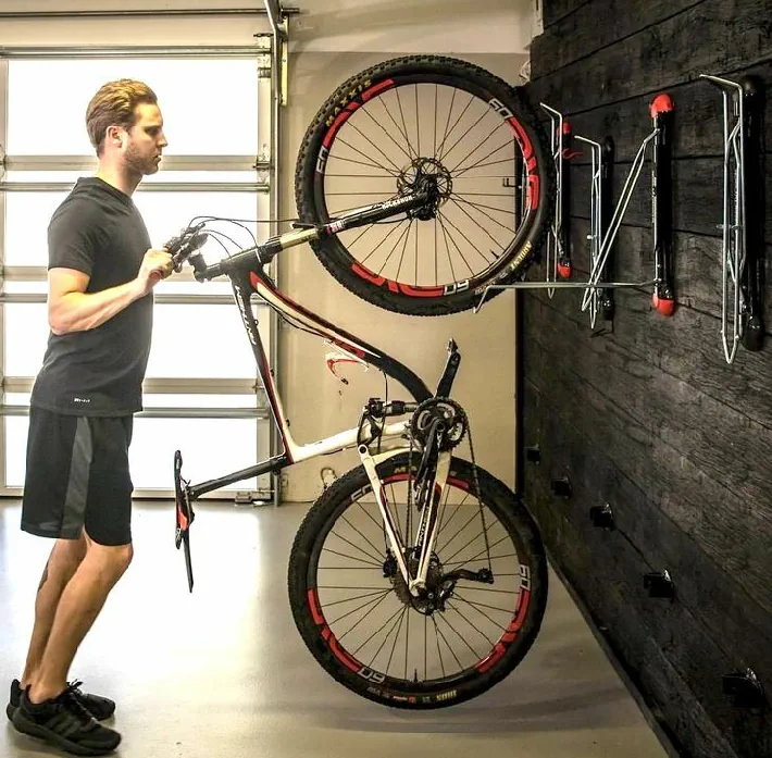 person storing an electric bike in a garage on a storage rack