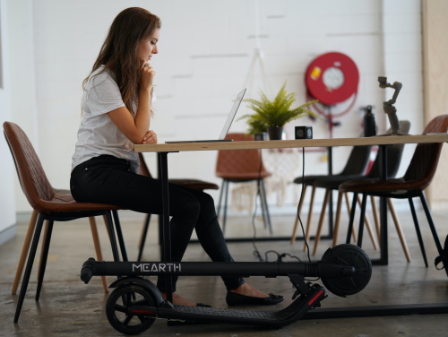 A foldable e-scooter stored under a desk