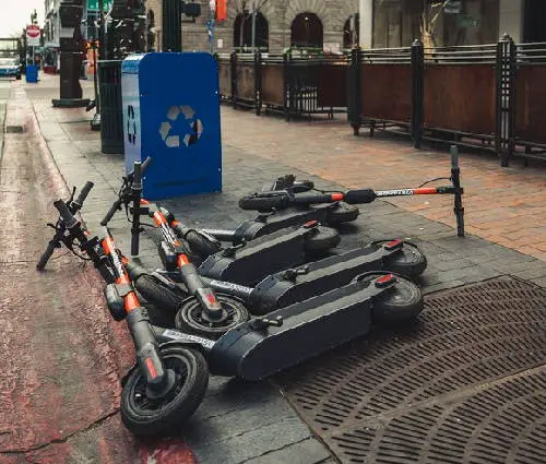 several rental electric scooters on a sidewalk