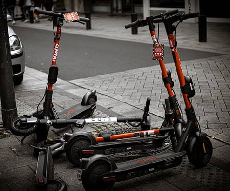 several Spin rental electric scooters on a sidewalk