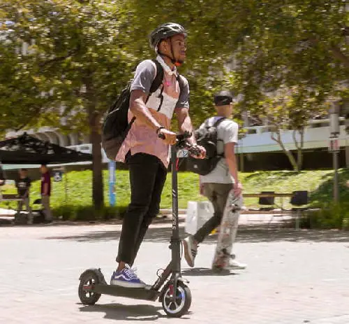 student with a backpack on an electric scooter