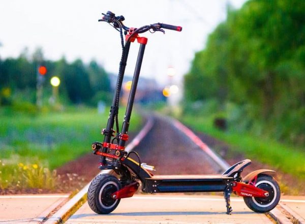 side view of the Techlife X9 electric scooter leaning on its stand standing on a railroad